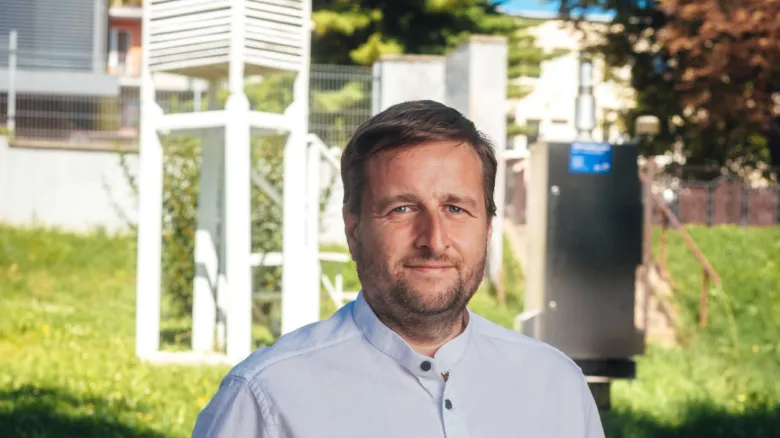 Muž stojí venku před vybavením pro měření klimatických podmínek.