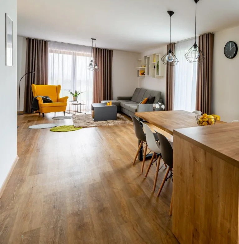 Moderní obývací pokoj s dřevěnou podlahou a žlutým křeslem.