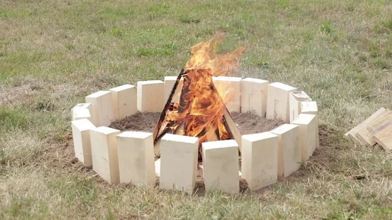 Oheň v kamenném ohništi na trávníku.