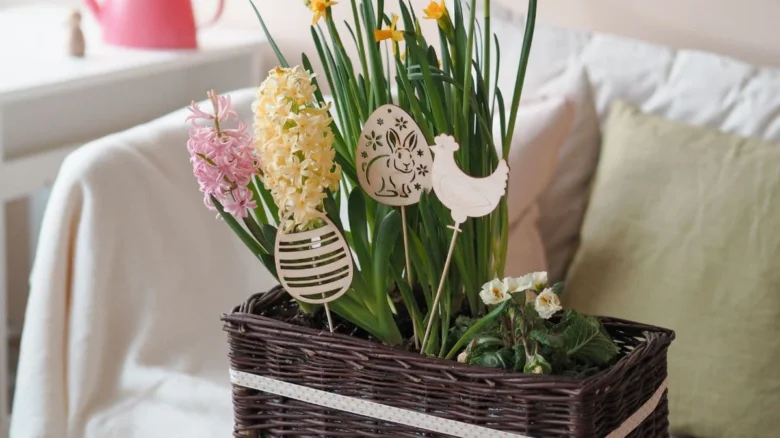 Jarní květiny v košíku s easter dekoracemi na gauči.
