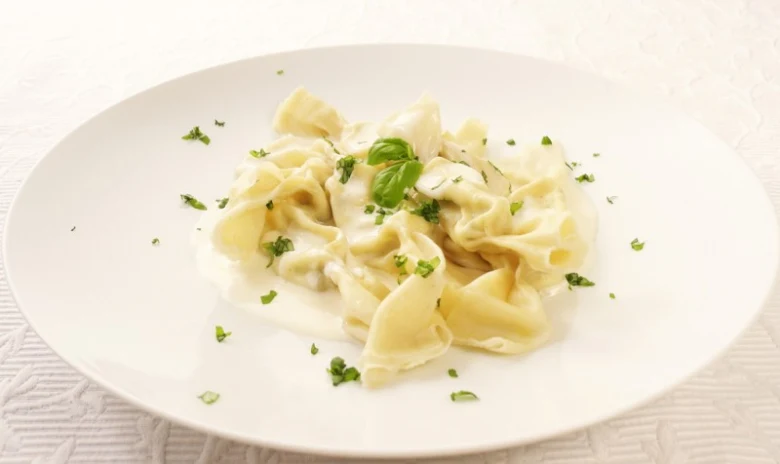 Připravené ravioli s bílým omáčkou na talíři.