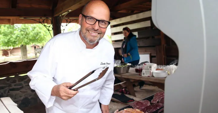 Šéfkuchař připravuje krkovici na venkovním grilu.