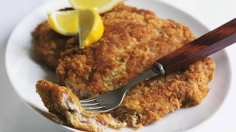 Hot meat cutlet with crispy breading, lemon slices.