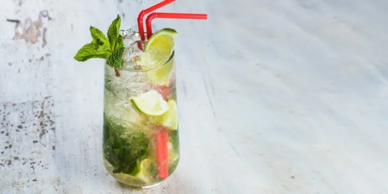 Hotový Mojito s limetkou a mátou v sklenici.