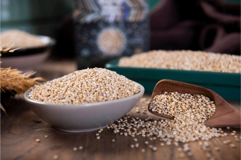 Bílá quinoa v miskě a dřevěné lžíci na dřevěném stole