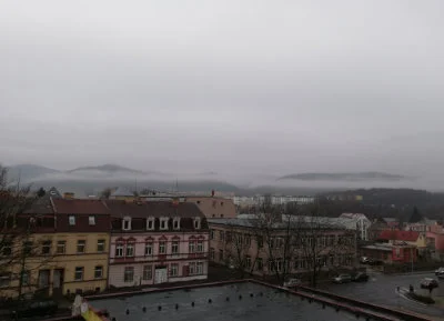 Šedé vrstevnaté mraky zakrývající město i hory.