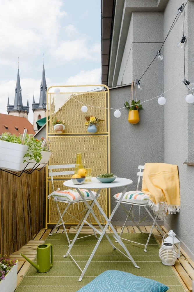 Malý balkon s žlutým nábytkem a rostlinami.