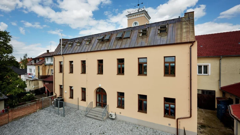 Mansardová střecha s okny na fasádě budovy.