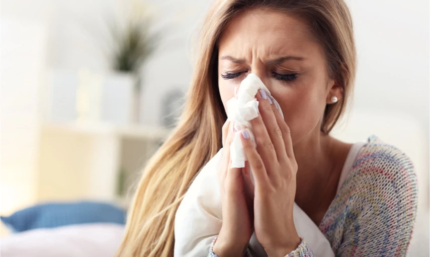 Woman blowing nose with tissue