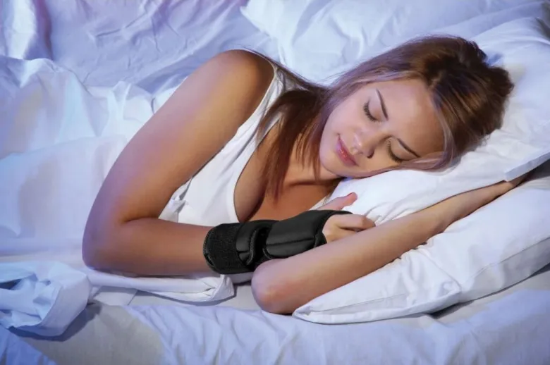 Žena spí s ortézou na ruce.