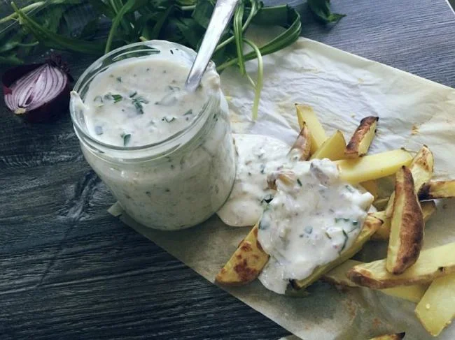 Jogurtový dip s bylinkami podávaný se smaženými bramborovými hranolky.