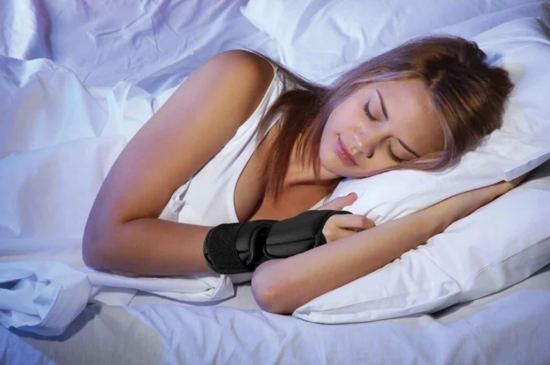 Žena spí s ortézou na ruce v posteli.