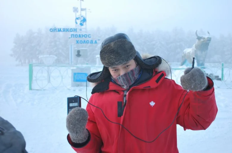 Muž u pomníku nejchladnějšího místa na světě s teploměrem.