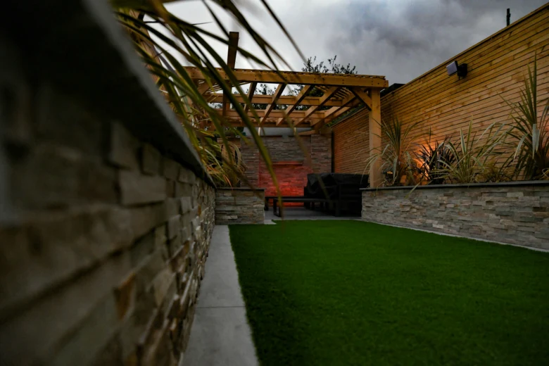 Dokončená dřevěná pergola v zahradním pozadí s umělou travou.