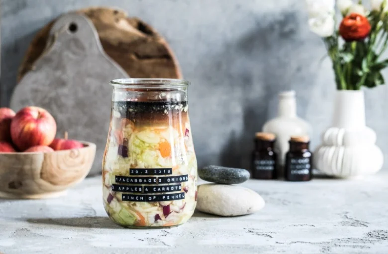 Sklenice s fermentovanou zeleninou se zobrazenými ingrediencemi.