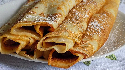 Zlaté palačinky posypané cukrem na talíři