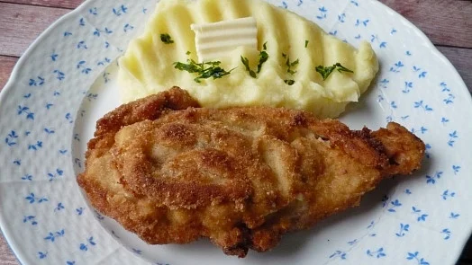 Hotová řízka s bramborovou kaší na talíři