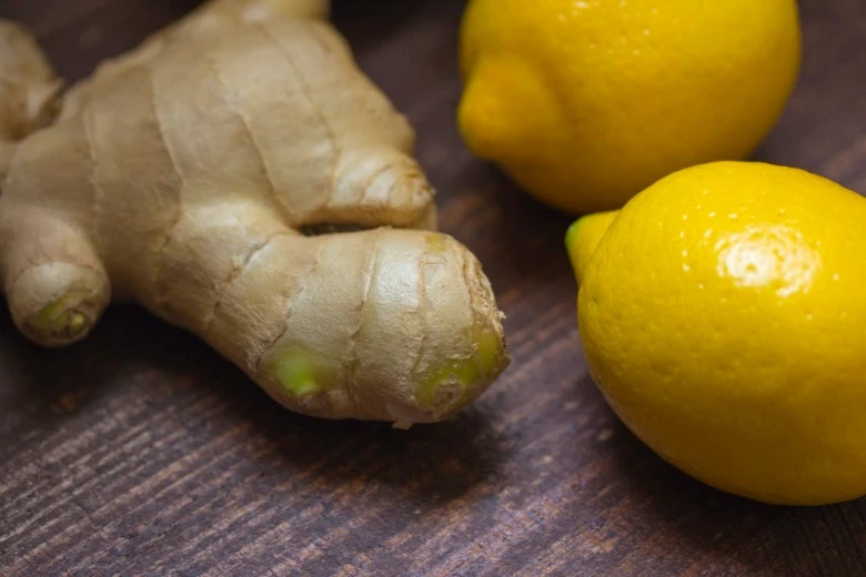 Čerstvý zázvor a citrony na dřevěném povrchu.