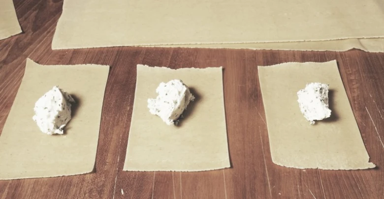 Příprava raviolí: plněná těsta na dřevěném stole.
