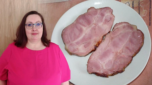 Dvě plátky nakládaného masa na talíři vedle ženy.