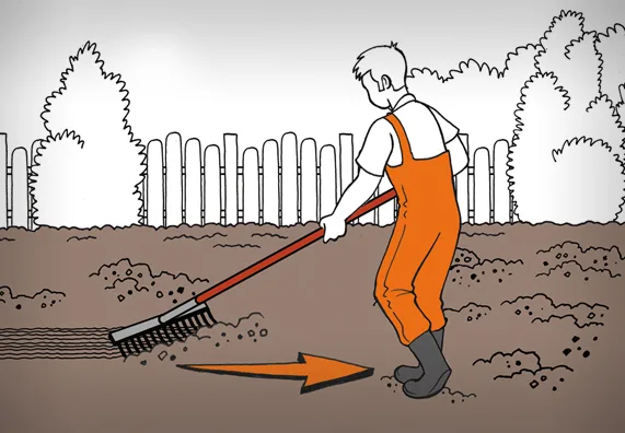 Muž roztahává trávník hrábem před zaséváním.