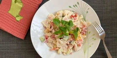Pasta salát s omáčkou na bílém talíři s bazalkou