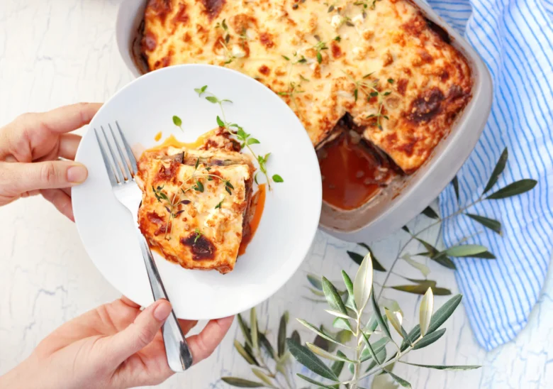 Příprava středomořské lasagne s bramborami na bílém talíři.