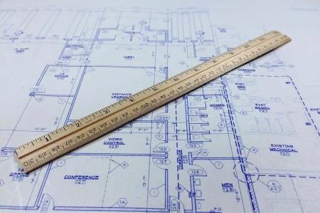 Pravítko na architektonickém plánu pro měření podlahové plochy.