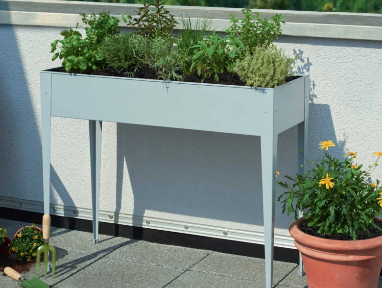 Zvýšený záhon s bylinkami na balkóně ukazuje správné založení zahrady.