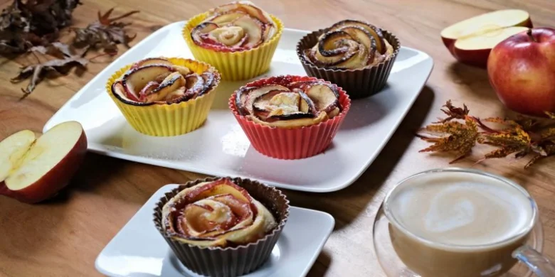 Jablečné muffiny se skořicí s kávou na dřevěném stole.