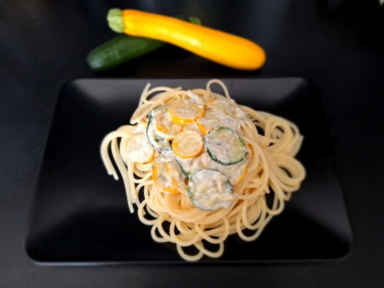 Spaghetti s cuketou v krémové omáčce na černém talíři.