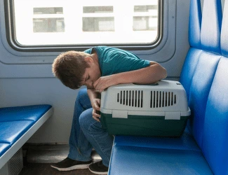 Muž spí v metru s krabicí pro zvířata.