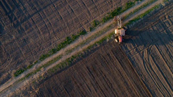 Traktor pracuje na poli, ukazuje přístup k pozemku.