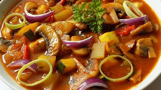 Hot plát s žampiony, zeleninou a cibulí v misce.